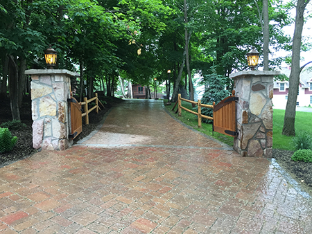 Paver Driveway with Stone Pillars and Wooden Gates